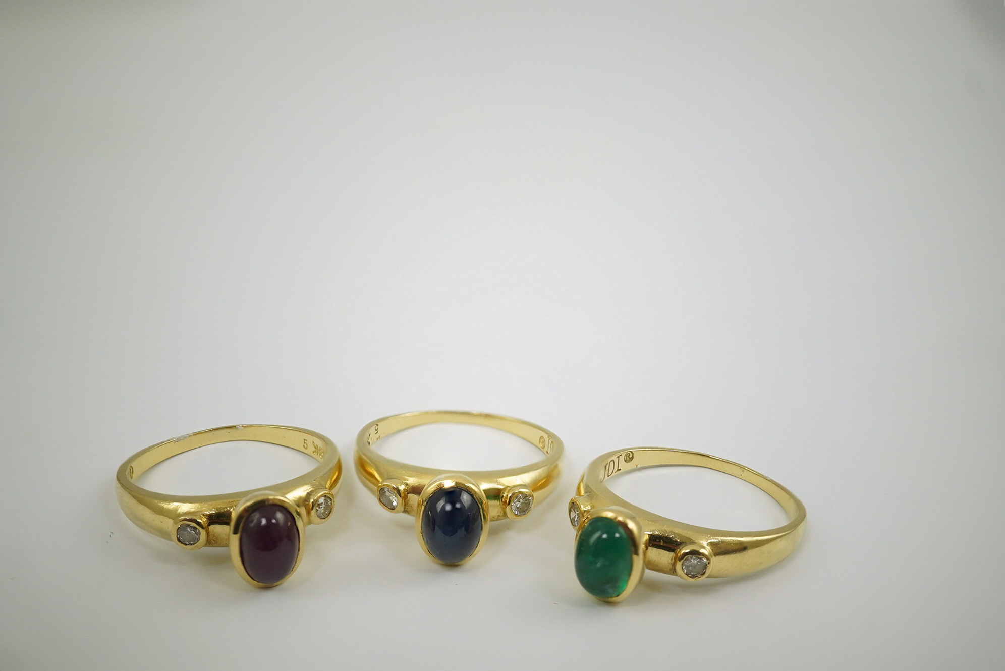 A suite of three modern 18k gold and gem set rings